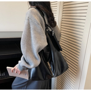 Macro shot of minimalist black matte leather tote with silver hardware and small pouch
