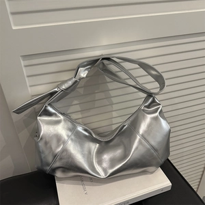 Silver metallic hobo underarm bag with large knot detail and geometric stitching on books