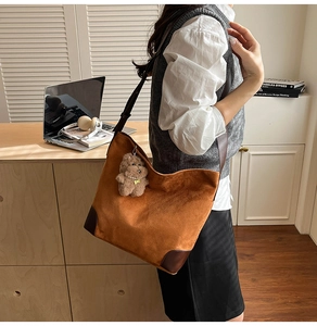 Close-up of caramel corduroy tote bag with brown leather details and a cute bear charm