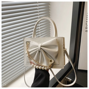 Détail du sac à main blanc carré avec grand nœud élégant et chaîne en perles dorées fines