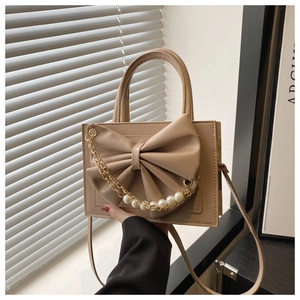 Détail du sac beige avec grand nœud et chaîne décorative dorée ornée de perles