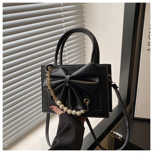 Détail du sac noir en cuir PU mat avec grand nœud et décoration de perles