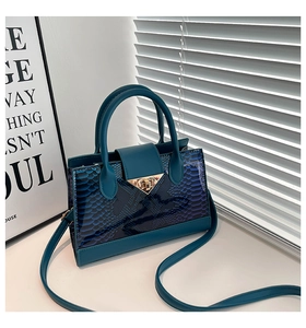 Dettaglio borsa blu scuro trama coccodrillo con chiusura a triangolo d'oro e tracolla