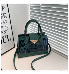 Dettaglio della borsa verde smeraldo con trama a serpente e chiusura dorata a triangolo