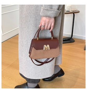 Detail of herringbone texture and gold M hardware on a vintage crossbody baguette bag