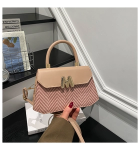 Detail of elegant two-tone crossbody bag with gold M-buckle and textured pattern