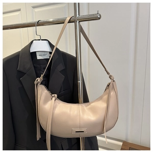 Détail du sac demi-lune beige avec glands en cuir et plaque métallique décorative