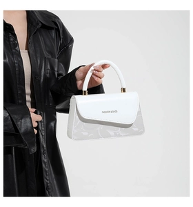 Detalle de bolso cuadrado blanco asimétrico con texto de moda y hebilla metálica dorada