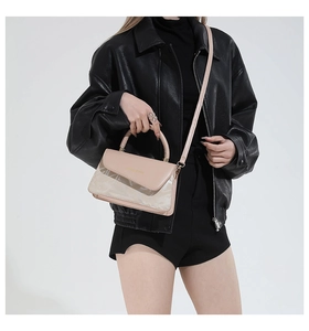 Detalle de bolso bandolera de cuero rosa con herrajes dorados y letras de moda