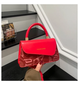 Detalle del bolso rojo con letras doradas y patrón de lujo en relieve