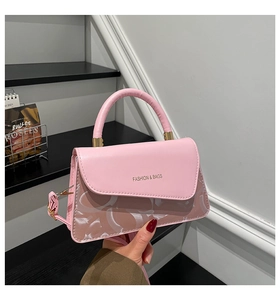 Detalle de bolso en cuero rosa con asa curva y letras doradas de Fashion & Bags