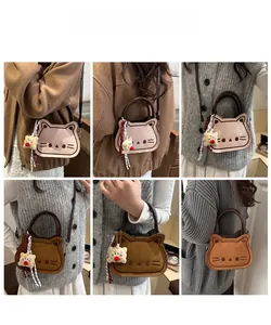 Detail view of cat-shaped crossbody bag with embroidery and plush pendant charm