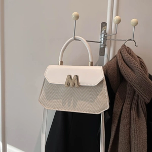 Minimalist cream leather and straw woven underarm bag with gold M logo on metal hook