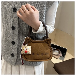 Detail of caramel cat-shaped handbag with embroidery and striped scarf charm