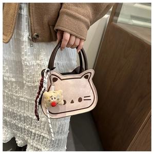 Detail van schattig kattenborduurwerk op beige suède tas met pluche hanger en handvat