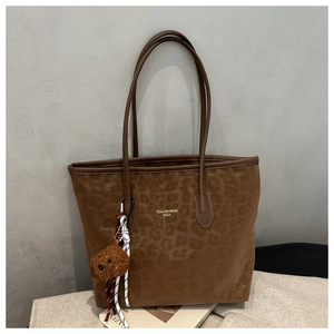 Detailed view of brown tote bag with leopard print and cute teddy bear charm