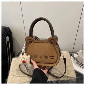 Detailed close-up of brown cat-shaped handbag featuring fine embroidery and plush charm