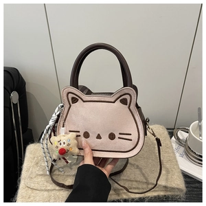 Detail of sweet cat-shaped embroidery on textured matte handbag with plush charm