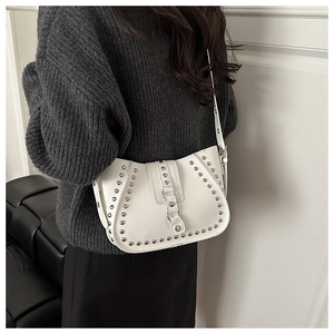 White rivet saddle bag shown on model wearing a grey sweater for a minimalist aesthetic