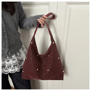 Close-up of burgundy leopard embossed leather tote with gold stud details