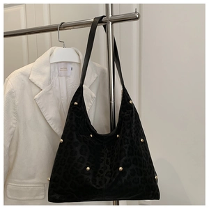 Dettaglio della borsa tote leopardata con borchie metalliche e tracolla in pelle nera