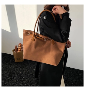Detail van de suède shopper in karamel met metalen gesp op de schouder van model