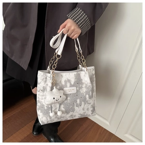 Detail of printed tote bag featuring star pattern and cute cloud charm accessory