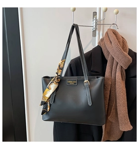 Detail of black leather tote bag with printed silk scarf wrap on handle and embossed logo