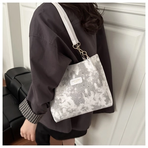 Detail of starry marble print tote with gold rings and leather logo tag on shoulder