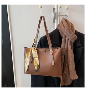 Brown leather tote bag with silk scarf detail hanging in a stylish autumn fashion scene