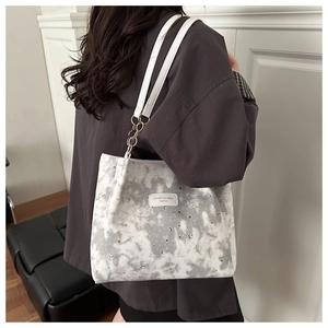 Close-up of a white tote bag with celestial star prints and leather shoulder strap detail