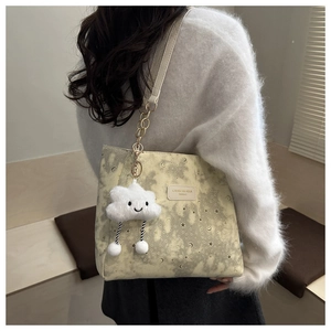 Close-up of beige tote bag with star patterns and plush cloud charm on model back