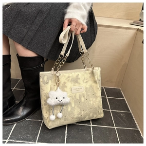 Detail of printed tote bag with chain strap and cute cloud charm on shoulder