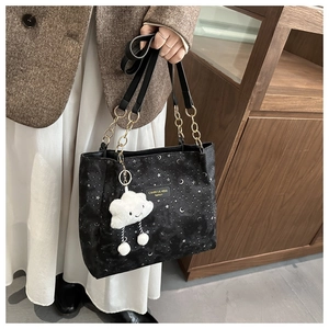 Detail of black tote bag with silver star moon print, chain strap and cloud plush charm