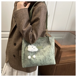 Close-up of light green tote bag with star and moon patterns and a cloud charm