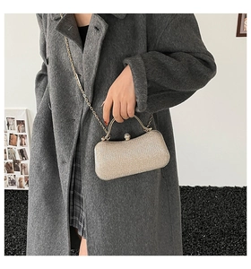 Detail of champagne gold sequined evening clutch with metal handle on a grey wool coat