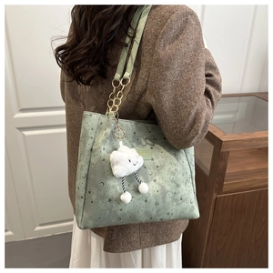 Detail of mint green tote bag with star patterns, cloud charm, and chain strap