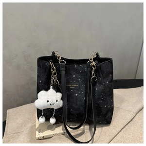 Detail of black tote bag with silver star prints, gold chains, and cloud charm