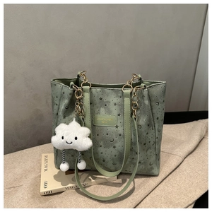 Detail of green tote bag with star-moon cutouts, brand logo and plush cloud charm