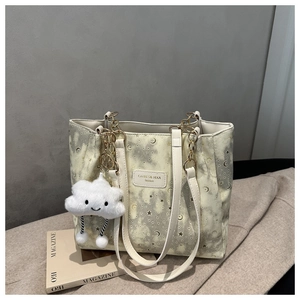 Detail of star-moon pattern tote bag with gold chain and white fluffy cloud charm
