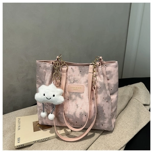 Detail of pink starry tote bag with galaxy prints, metal chain, and plush cloud charm