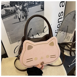 Detail der rosafarbenen Katzen-Handtasche mit Stickerei und Goldbeschlägen auf Strick