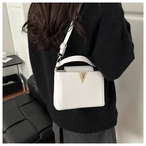 Close-up of white lychee leather bucket bag with gold V hardware worn by a model