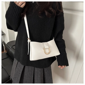 Détail du sac à bandoulière en cuir blanc avec une boucle fer à cheval dorée