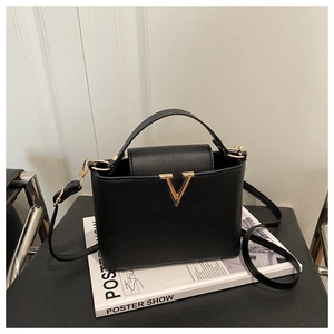 Detailed view of black lychee grain leather bucket bag with gold V-shaped metal buckle