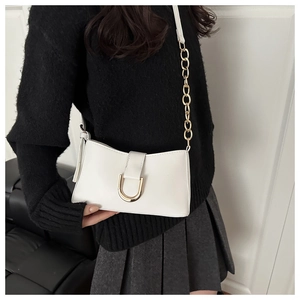Détail du sac à bandoulière blanc avec boucle dorée en U et bandoulière en chaîne
