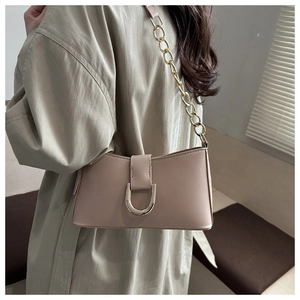 Sac baguette beige élégant avec boucle en D dorée et bandoulière chaîne sur modèle