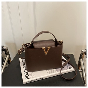 Detail of dark brown pebble leather handbag with gold V-shaped buckle and top handle