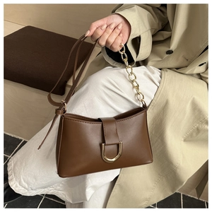 Détail du sac à main marron rétro avec boucle dorée en U et bandoulière en chaîne