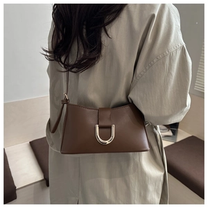 Gros plan sur un sac baguette en cuir marron foncé avec une grande boucle en métal argenté